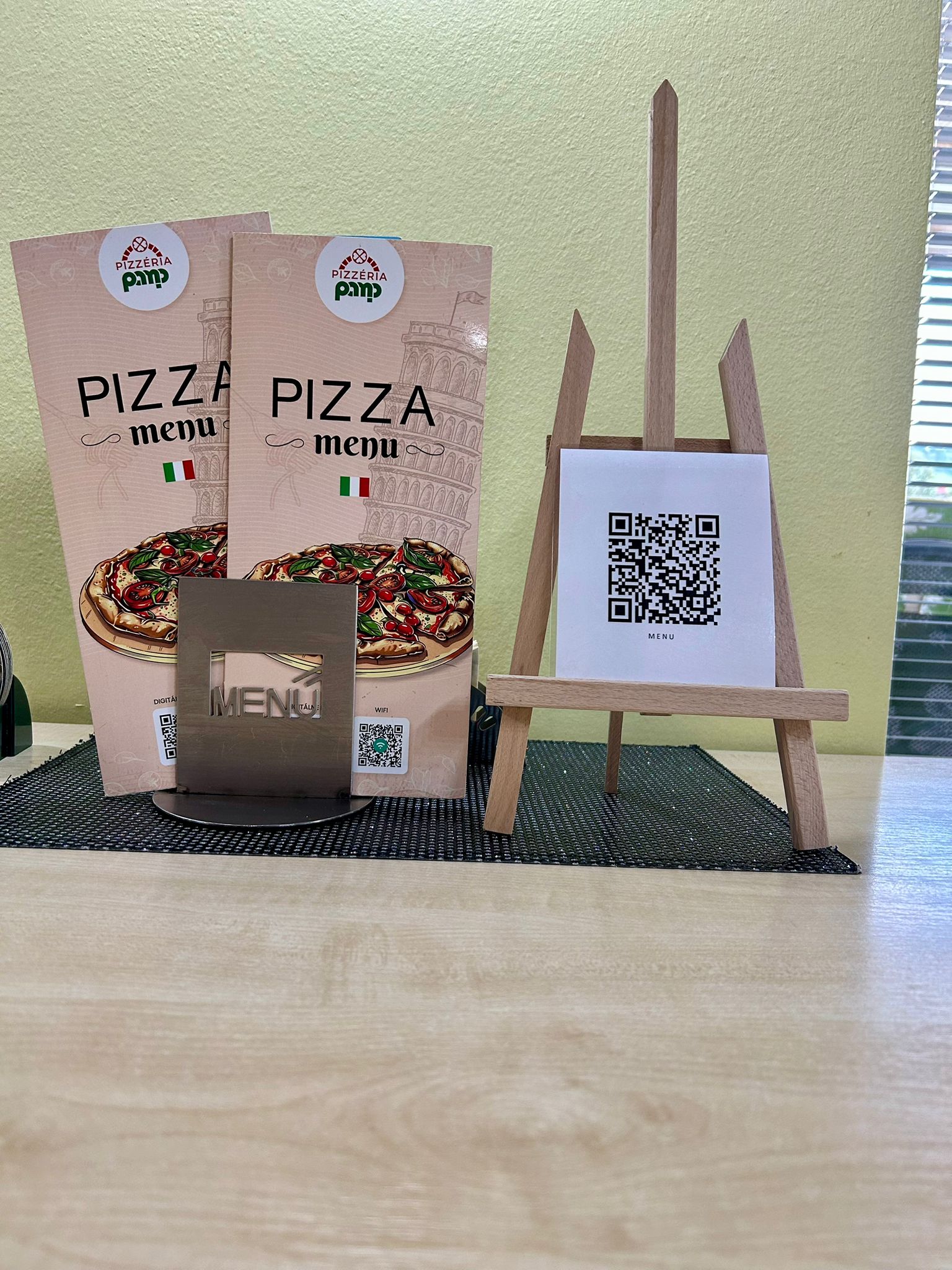 Printed pizza menus with a QR code on a wooden stand in a restaurant, offering customers access to the digital menu using their smartphone.